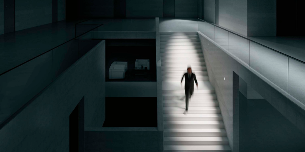 Una persona bajando una escalera iluminada en la oscuridad.