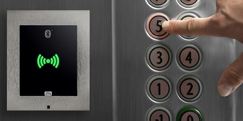 Un lector de tarjeta RFID y una mano pulsando un botón del piso del ascensor.