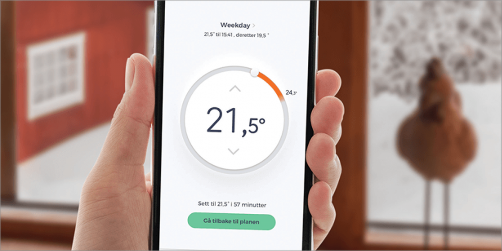 Una mano con un móvil marcando la temperatura interior de un hogar.