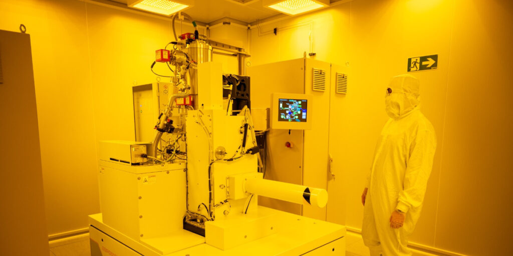 Equipo de nanofabricación y una persona con indumentaria de sala blanca en el IMB-CNM de Barcelona