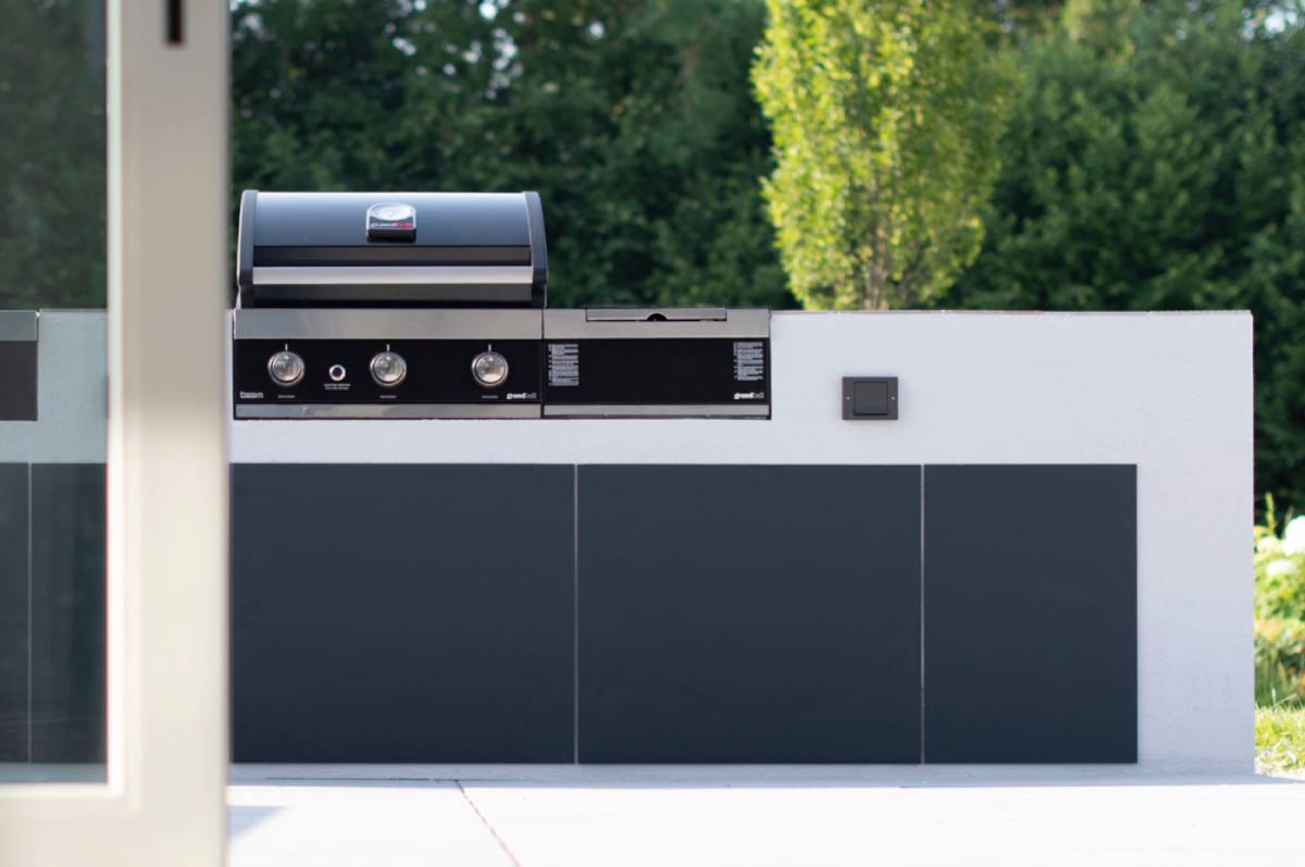 Cocina de exterior con iluminación y tomas de corriente integradas de Gira para usar terrazas, porches y jardines gran parte del año