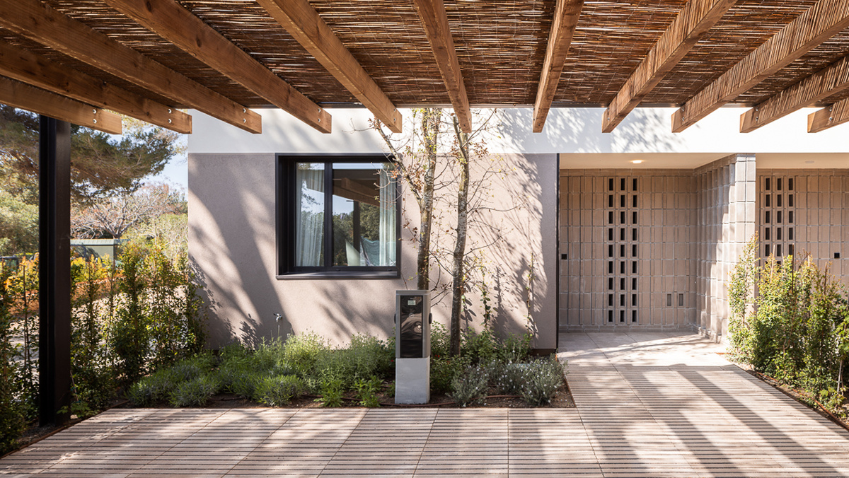 Cargador Simon Neon junto a una vivienda de Villas Ponent, bajo una pérgola de madera.